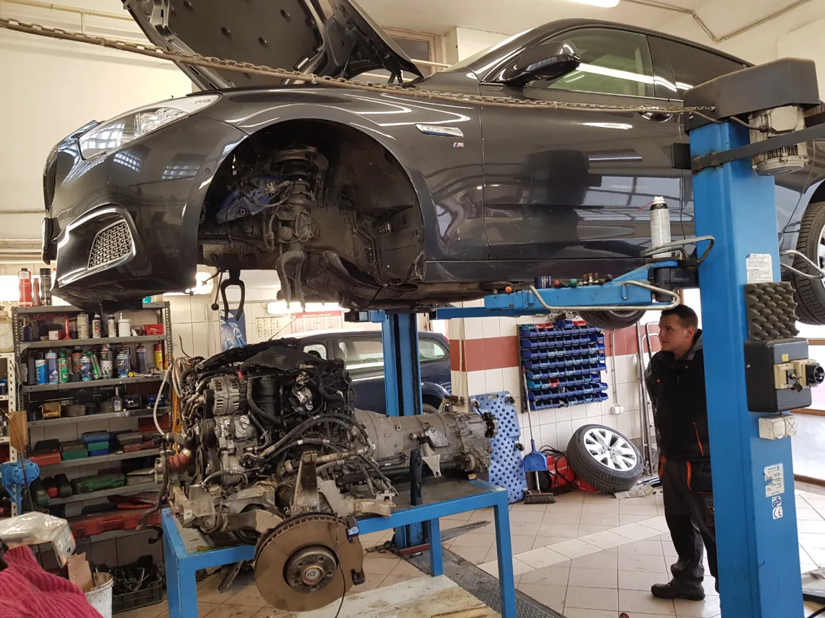 Autó emelőn, mellette a kiszerelt motor állványon